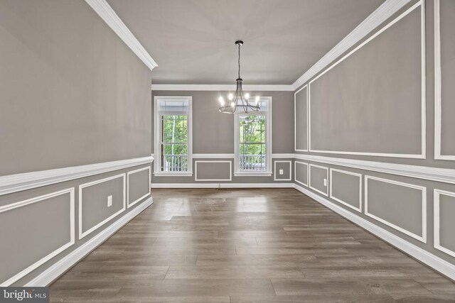 unfurnished dining area with an inviting chandelier, dark hardwood / wood-style flooring, and ornamental molding