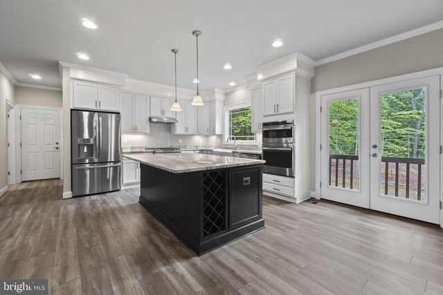 kitchen with pendant lighting, stainless steel appliances, a center island, and white cabinets