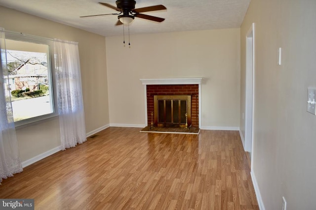 unfurnished living room with light wood-style floors, visible vents, a fireplace, and baseboards