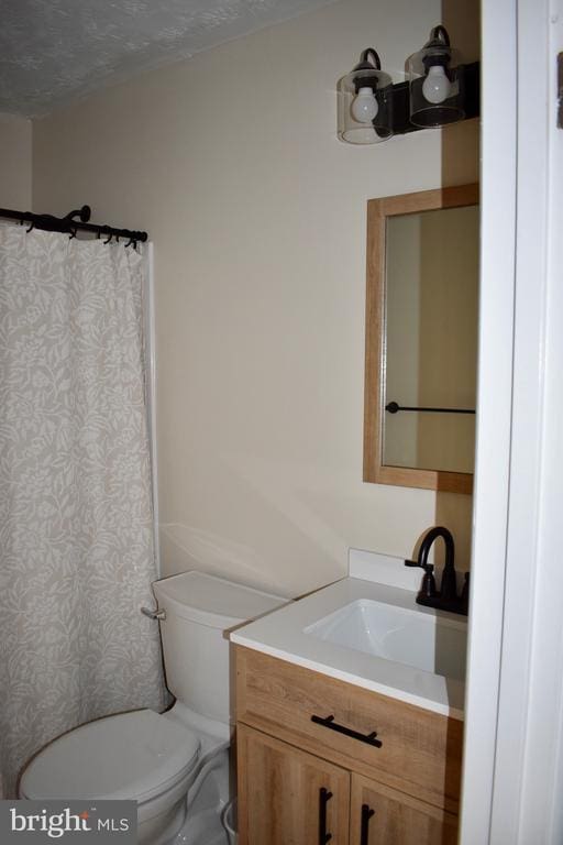 bathroom featuring a shower with shower curtain, vanity, toilet, and a textured ceiling