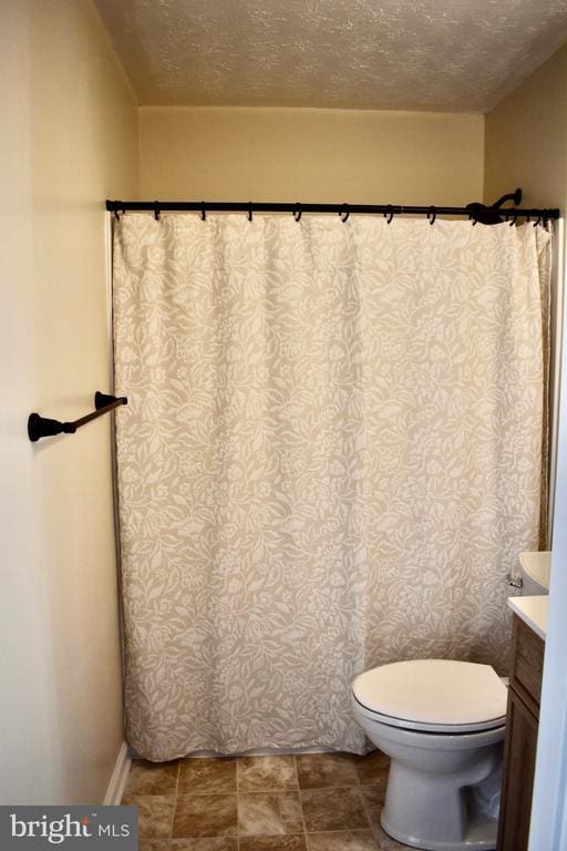 bathroom with toilet, a textured ceiling, and vanity