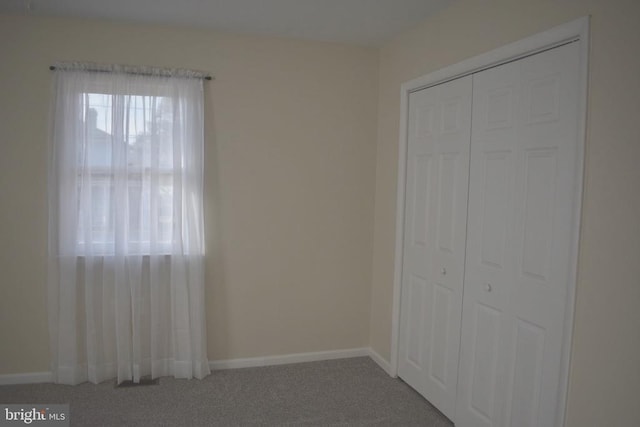 unfurnished bedroom with a closet, carpet flooring, and baseboards