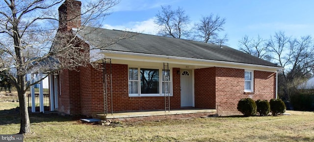 view of front of home with brick siding, a chimney, and a front yard