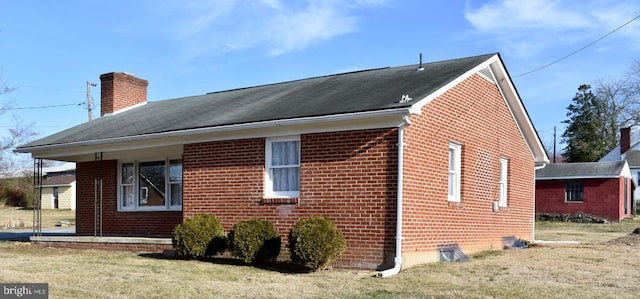 view of property exterior featuring brick siding, a yard, and a chimney