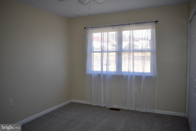 carpeted spare room with ceiling fan, visible vents, and baseboards