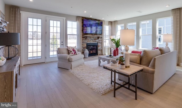 living room featuring a wealth of natural light, light hardwood / wood-style floors, and a large fireplace