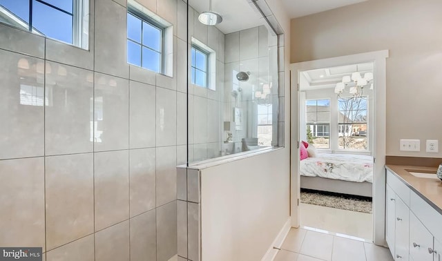 bathroom with a tile shower, vanity, and tile patterned floors