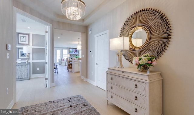 hallway featuring an inviting chandelier and light hardwood / wood-style flooring