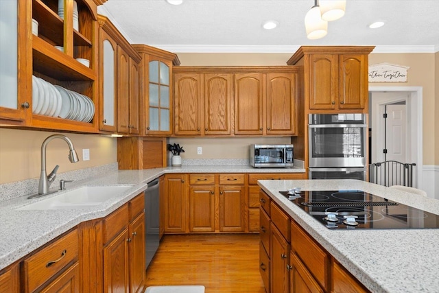 kitchen with sink, light hardwood / wood-style flooring, stainless steel appliances, ornamental molding, and light stone countertops