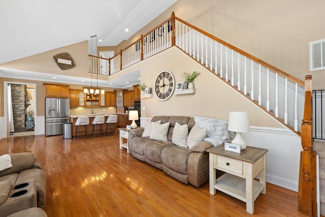 living room featuring sink, light hardwood / wood-style floors, and a high ceiling