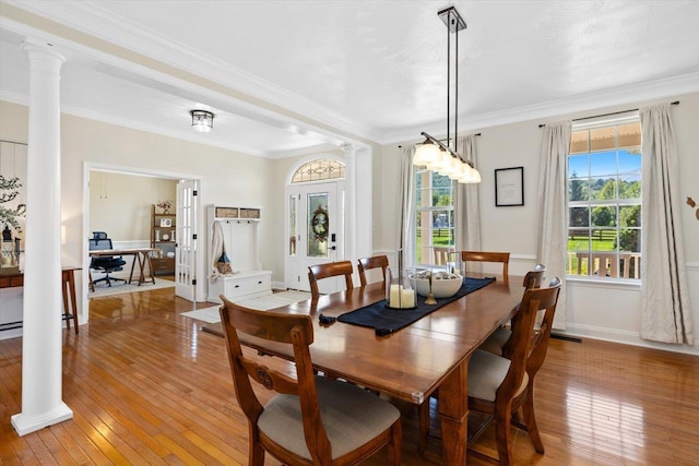 dining room featuring ornate columns, crown molding, and light hardwood / wood-style floors