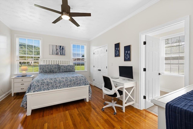 bedroom with hardwood / wood-style flooring, ornamental molding, ceiling fan, and multiple windows