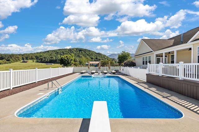 view of pool featuring a diving board, a mountain view, and a patio area