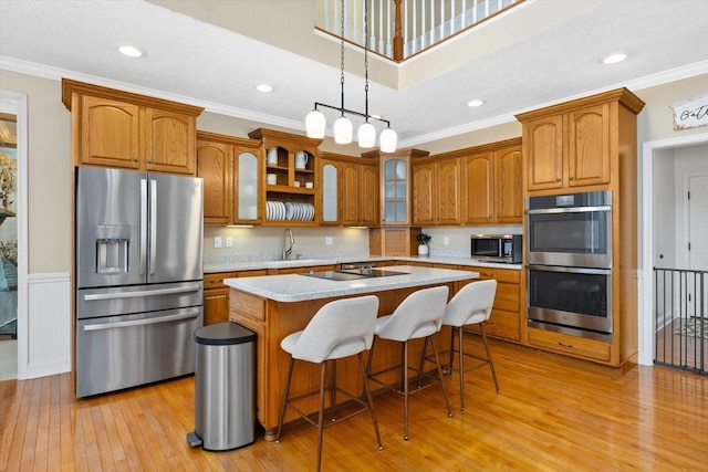 kitchen with a kitchen bar, crown molding, decorative light fixtures, a center island, and stainless steel appliances