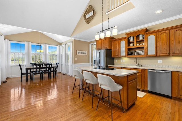 kitchen featuring a kitchen bar, sink, decorative light fixtures, a center island, and stainless steel appliances