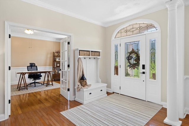 foyer entrance featuring hardwood / wood-style flooring, crown molding, and ornate columns