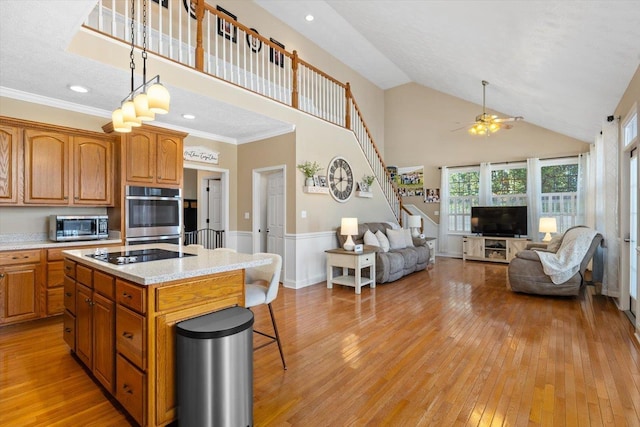 kitchen featuring a kitchen island, high vaulted ceiling, light stone counters, stainless steel appliances, and light wood-type flooring