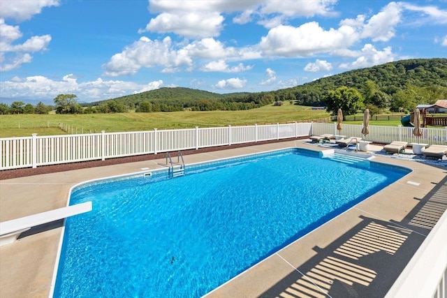 view of swimming pool featuring a patio and a diving board