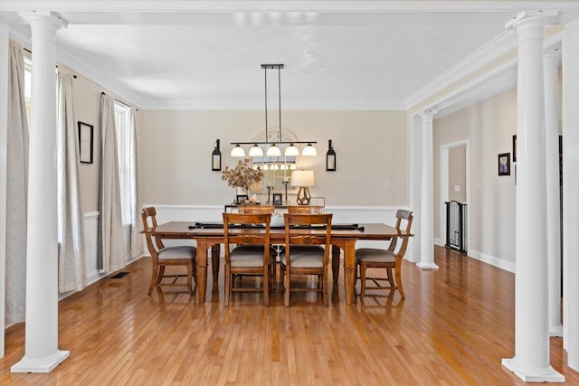 dining space with ornate columns, ornamental molding, and wood-type flooring