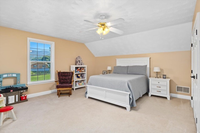 bedroom with lofted ceiling, ceiling fan, light colored carpet, and a textured ceiling