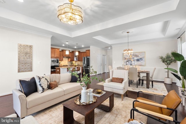 living room with a tray ceiling, recessed lighting, light wood-style flooring, a chandelier, and baseboards