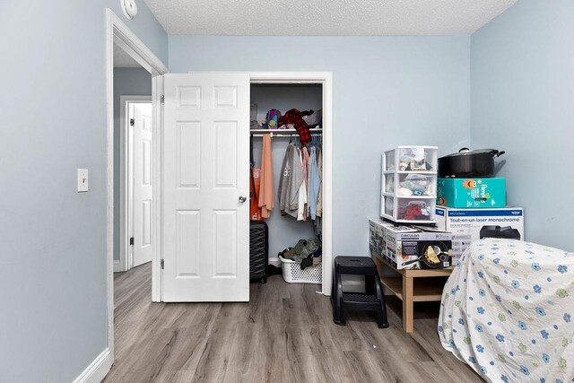 bedroom with a closet, a textured ceiling, and light hardwood / wood-style flooring