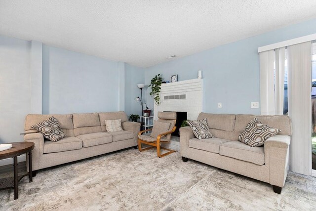 living room with a brick fireplace and a textured ceiling