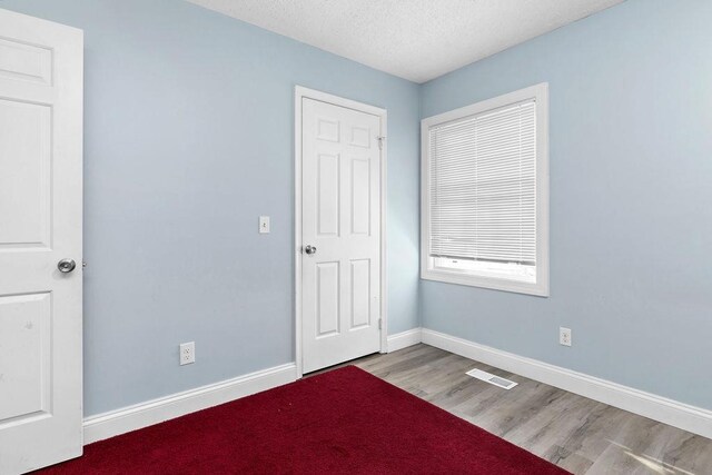 unfurnished bedroom with hardwood / wood-style floors and a textured ceiling