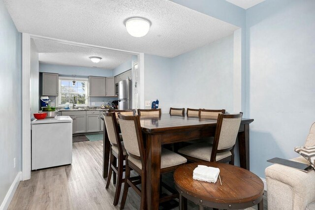 dining area with sink, light hardwood / wood-style flooring, and a textured ceiling