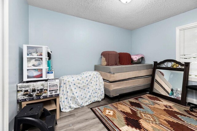 bedroom with hardwood / wood-style floors and a textured ceiling