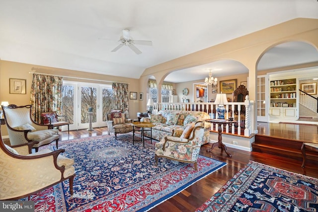 living room featuring lofted ceiling, ceiling fan with notable chandelier, and dark wood-type flooring