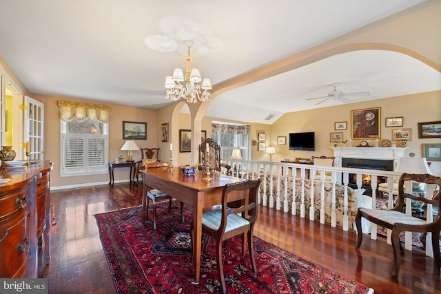 dining room featuring ceiling fan with notable chandelier, a healthy amount of sunlight, dark hardwood / wood-style flooring, and vaulted ceiling