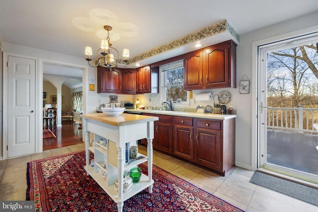 kitchen with sink, light tile patterned floors, hanging light fixtures, and a notable chandelier