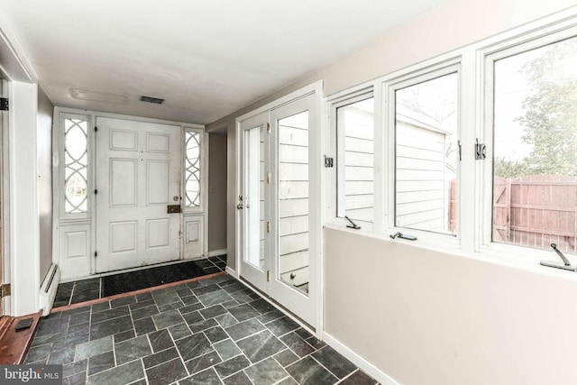 foyer entrance featuring stone finish flooring, baseboards, and visible vents
