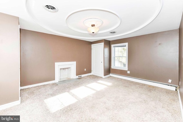 carpeted spare room with a fireplace with flush hearth, a tray ceiling, baseboards, visible vents, and a baseboard radiator
