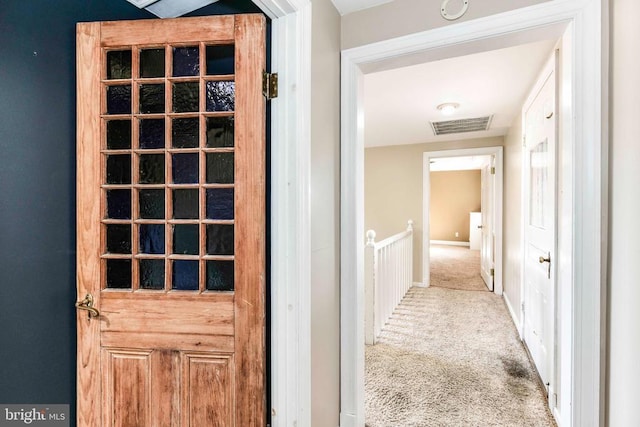 hallway featuring carpet floors, visible vents, and baseboards
