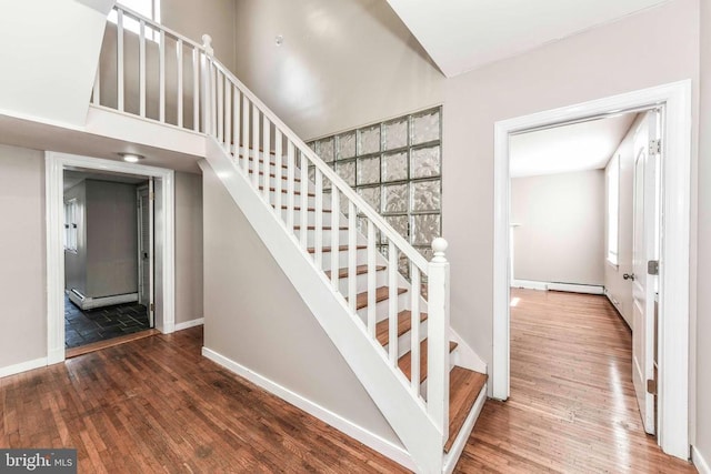 stairway featuring baseboards, wood finished floors, and a baseboard radiator
