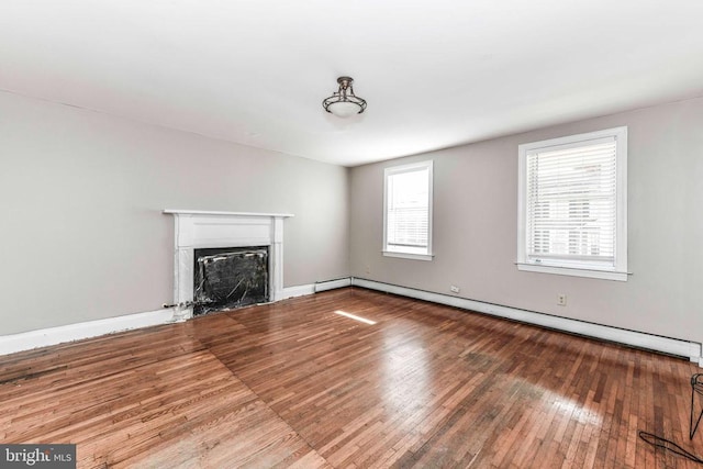 unfurnished living room with a baseboard heating unit, baseboards, wood finished floors, and a fireplace