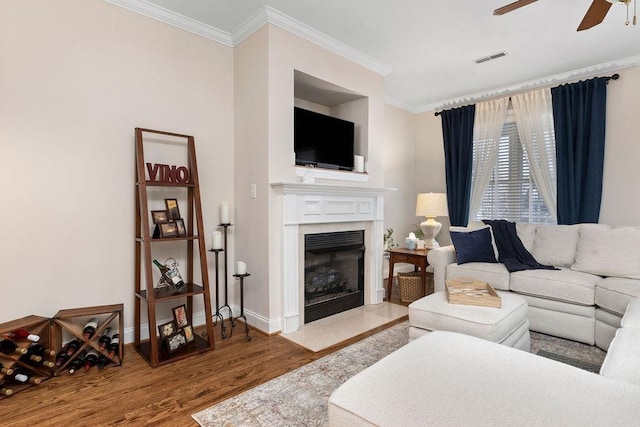 living room featuring crown molding, wood-type flooring, and ceiling fan