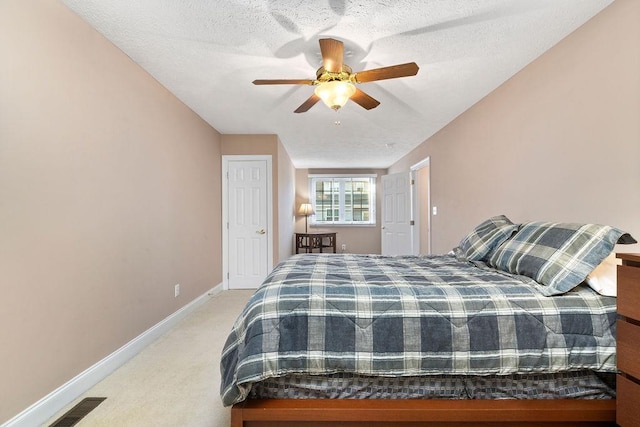 bedroom featuring light carpet, ceiling fan, and a textured ceiling