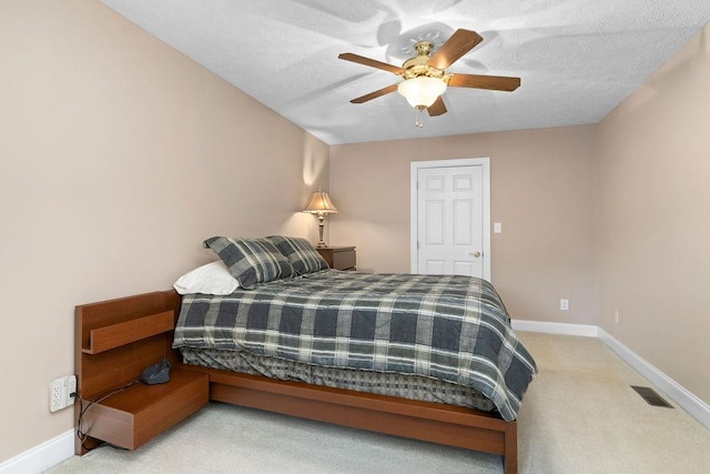 bedroom featuring light carpet, a textured ceiling, and ceiling fan