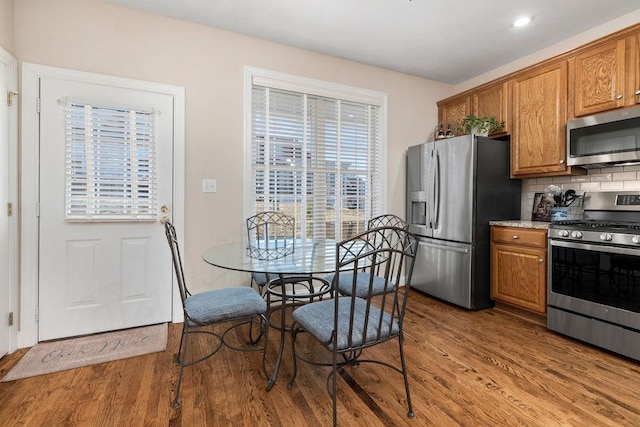 kitchen with tasteful backsplash, appliances with stainless steel finishes, and hardwood / wood-style flooring