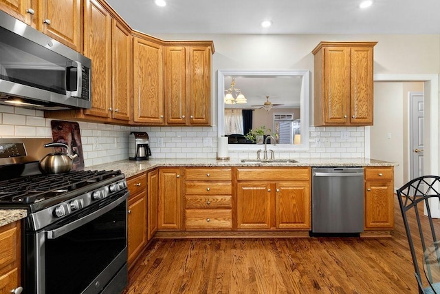 kitchen featuring sink, dark wood-type flooring, ceiling fan, stainless steel appliances, and light stone counters