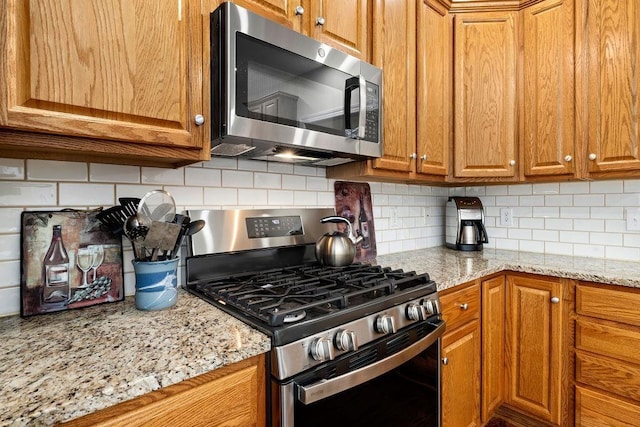 kitchen with tasteful backsplash, light stone countertops, and appliances with stainless steel finishes