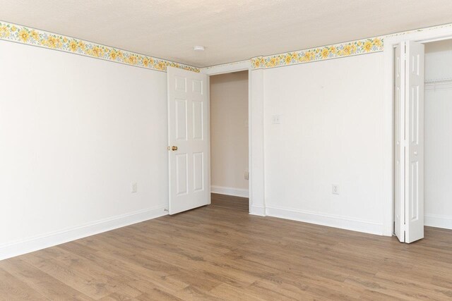 unfurnished bedroom featuring hardwood / wood-style flooring, a textured ceiling, and a closet