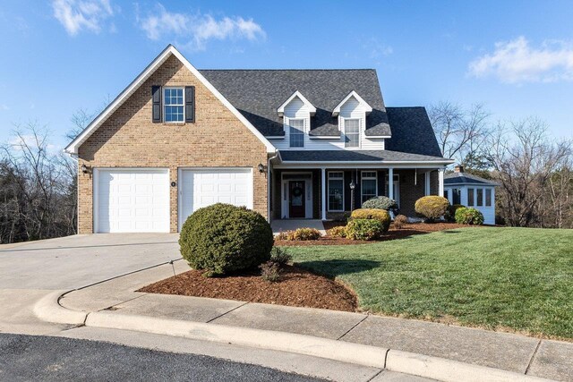 cape cod home featuring a garage, a front yard, and covered porch