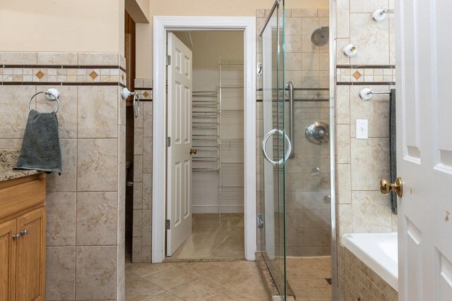 bathroom featuring vanity, tile patterned flooring, tile walls, and separate shower and tub