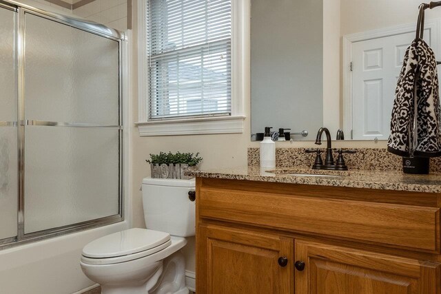 full bathroom with vanity, bath / shower combo with glass door, and toilet