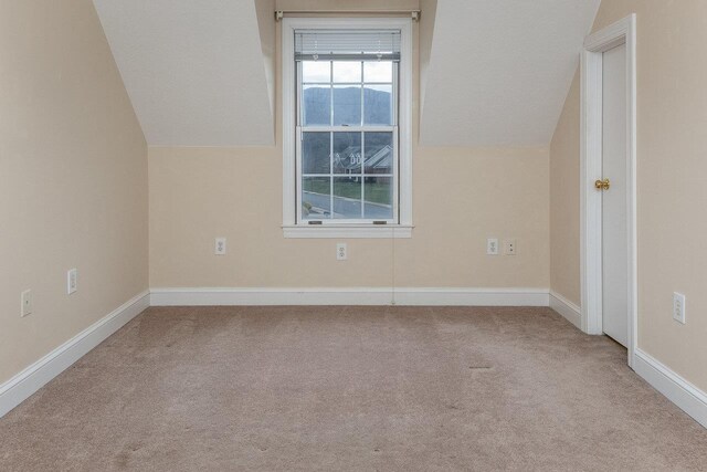 additional living space featuring light colored carpet and vaulted ceiling