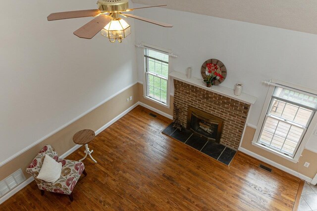 unfurnished living room with a brick fireplace, hardwood / wood-style floors, and ceiling fan